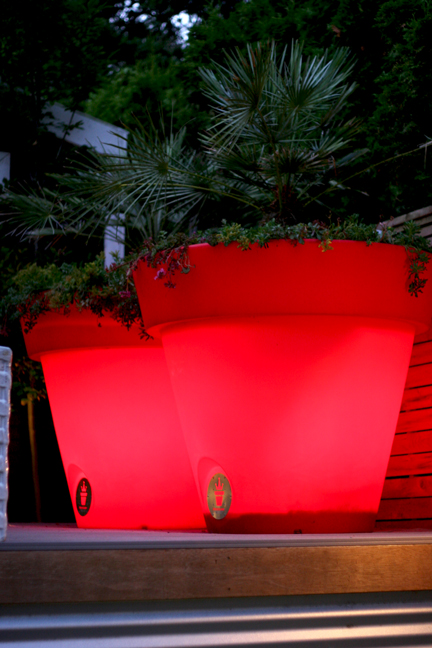 Giant red plastic plant pots lit from within. 